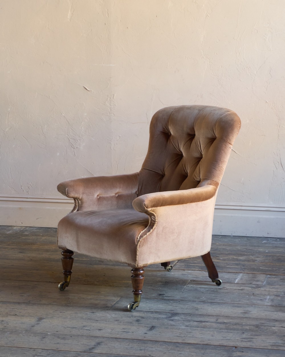 A Regency period spoon back armchair upholstered in taupe velvet with deep buttoning, turned mahogany front legs, and brass castors. View II