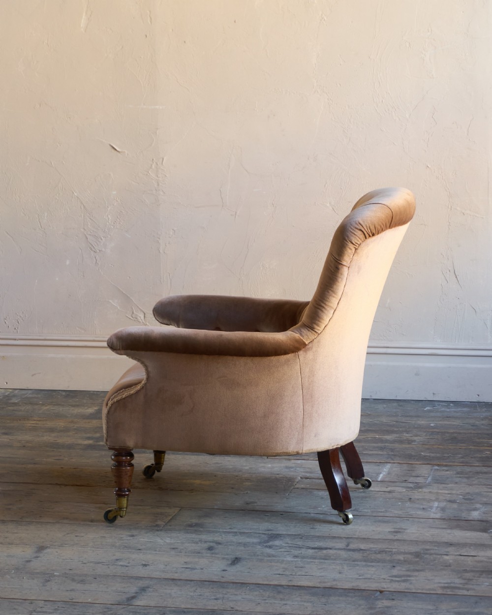 A Regency period spoon back armchair upholstered in taupe velvet with deep buttoning, turned mahogany front legs, and brass castors. View III