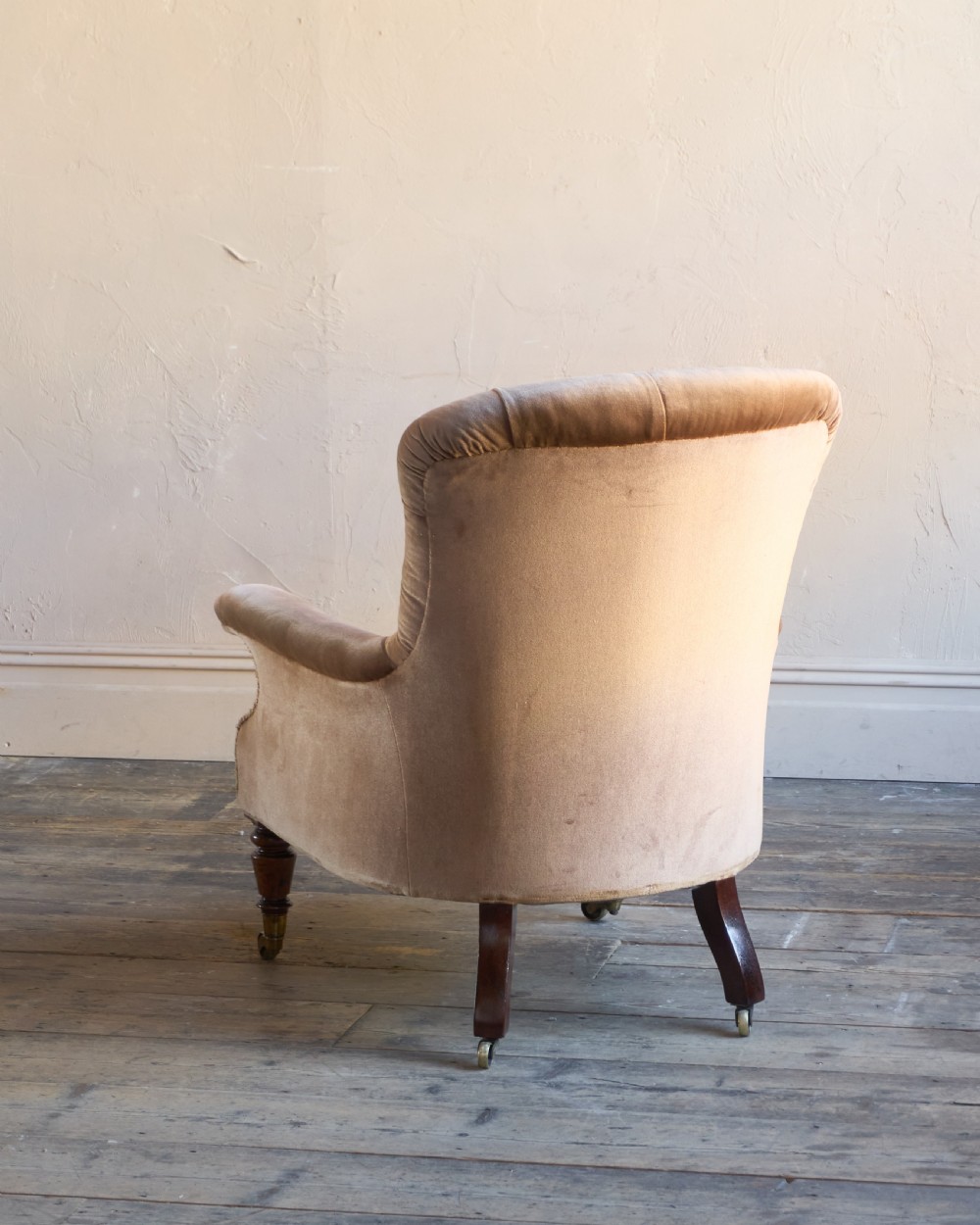 A Regency period spoon back armchair upholstered in taupe velvet with deep buttoning, turned mahogany front legs, and brass castors. View IV