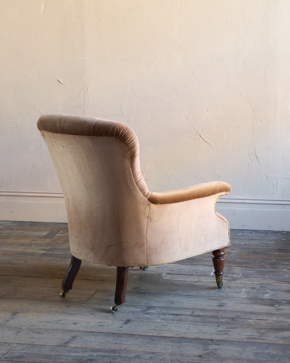 A Regency period spoon back armchair upholstered in taupe velvet with deep buttoning, turned mahogany front legs, and brass castors. View V
