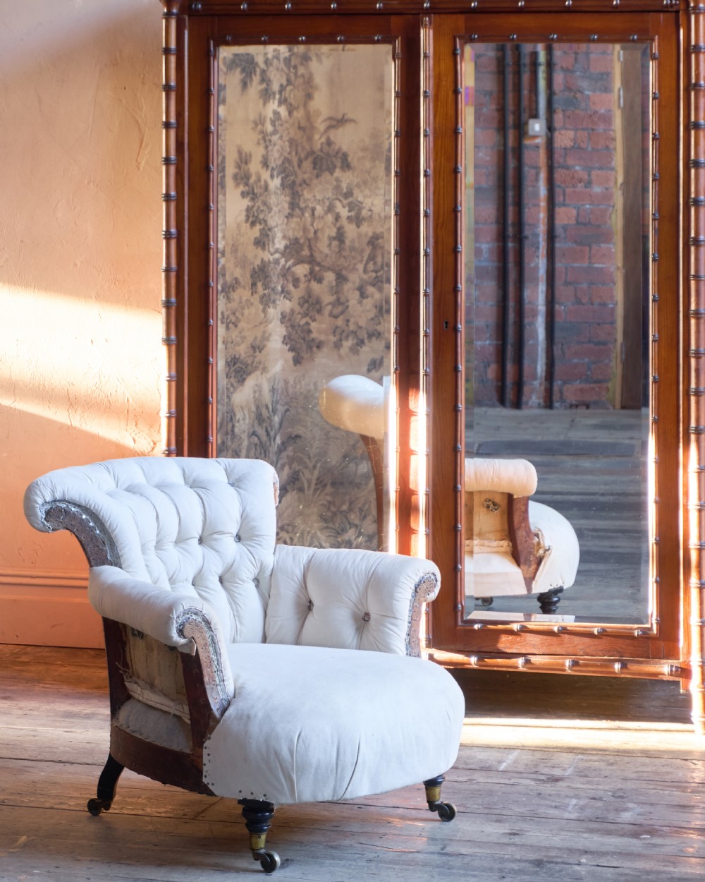 A 19th-century button-back armchair in off-white calico fabric with turned front legs resting on brass castors. View III