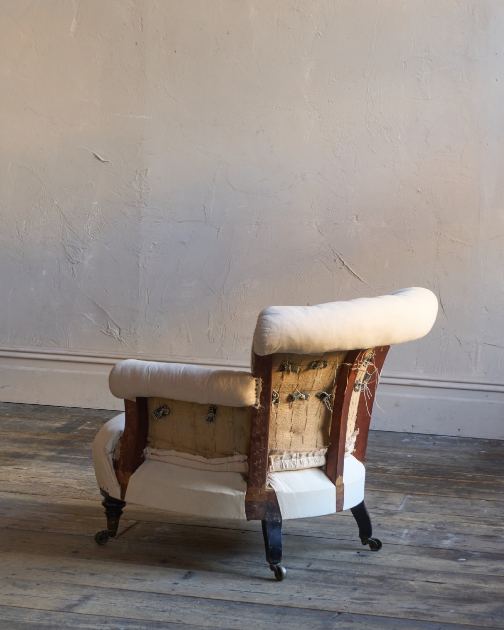 A 19th-century button-back armchair in off-white calico fabric with turned front legs resting on brass castors. View V