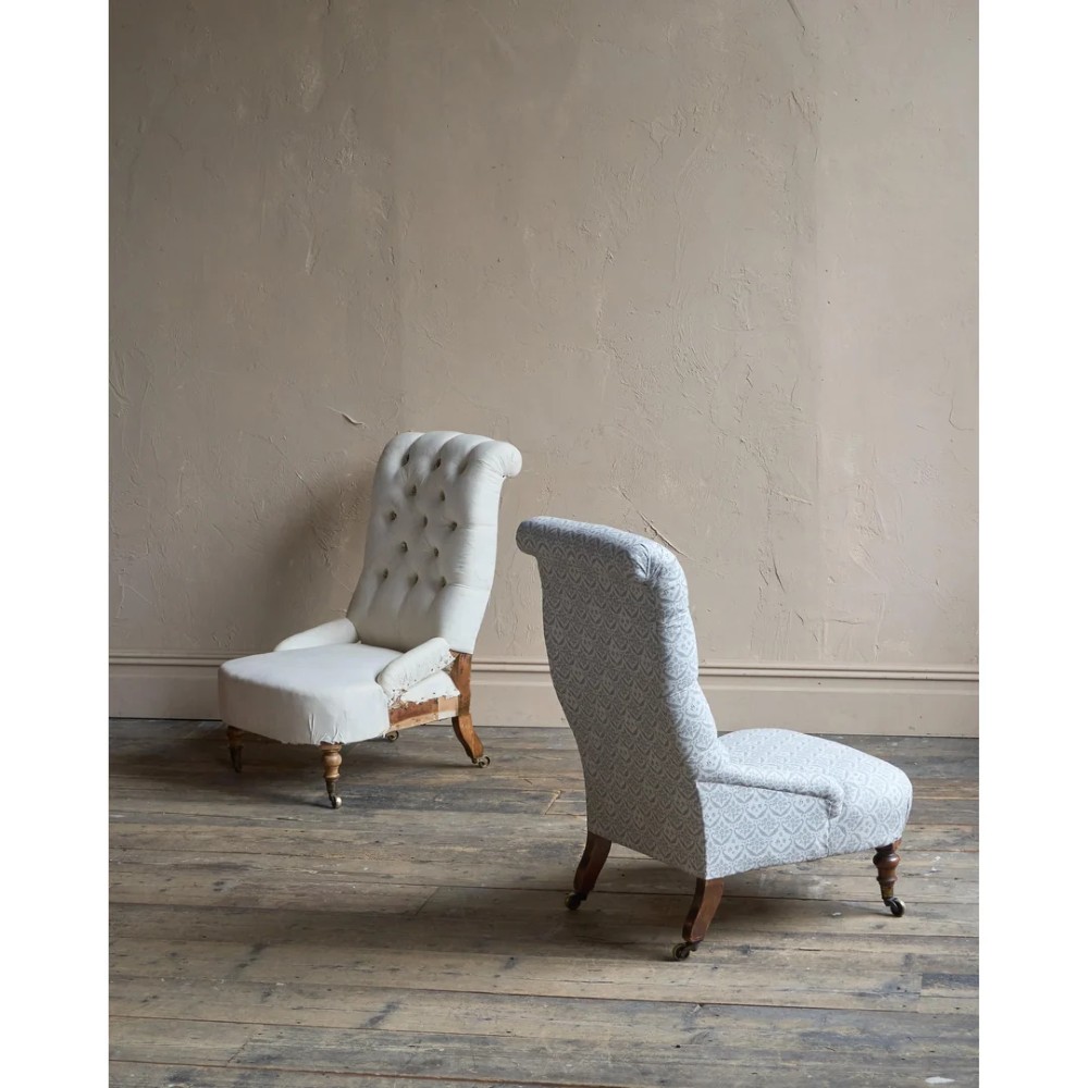 A pair of low Victorian button-back armchairs with turned wooden legs and brass castors, one in calico and one in patterned grey fabric. View III
