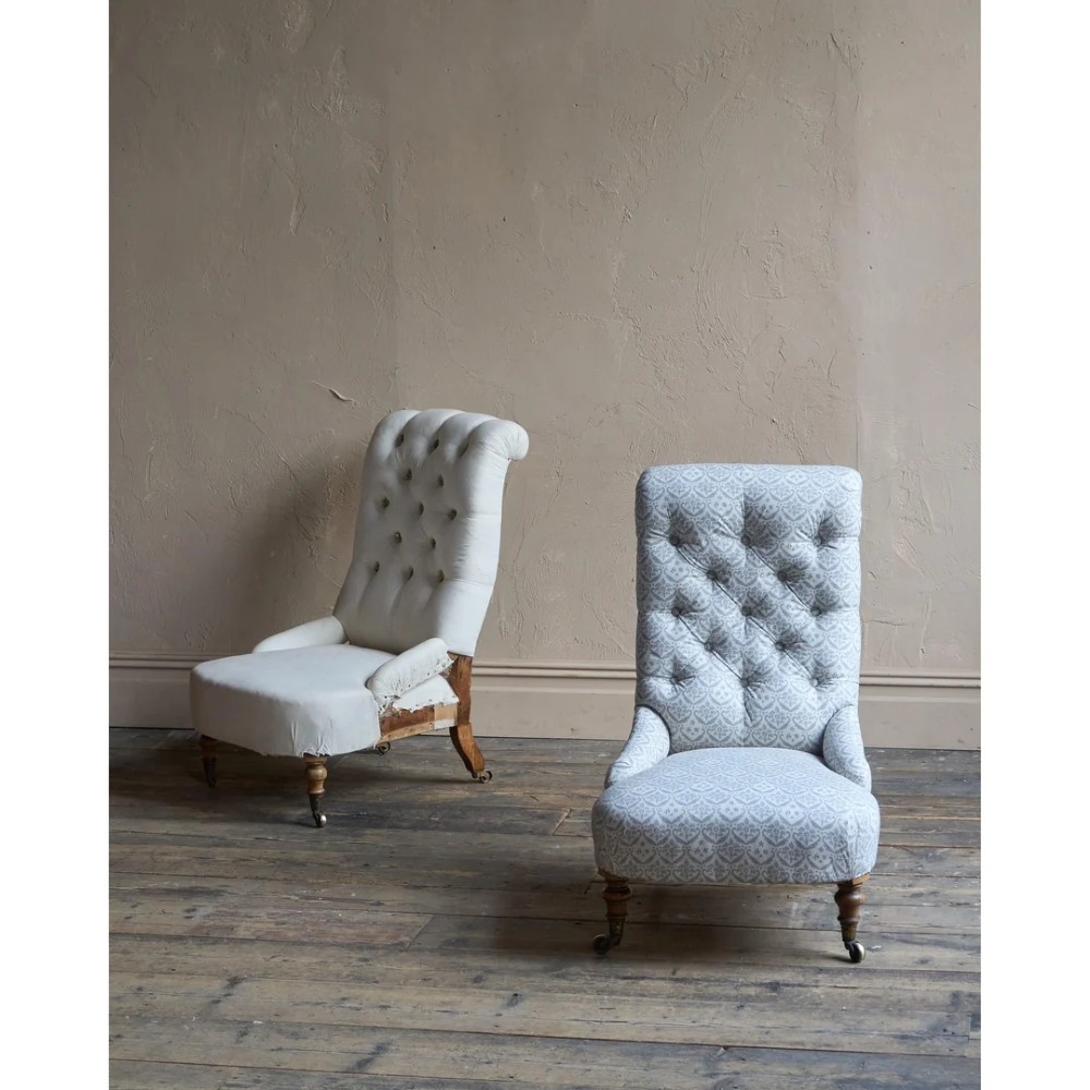 A pair of low Victorian button-back armchairs with turned wooden legs and brass castors, one in calico and one in patterned grey fabric. View VI