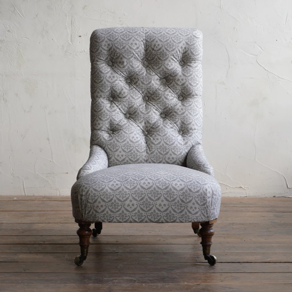 A pair of low Victorian button-back armchairs with turned wooden legs and brass castors, one in calico and one in patterned grey fabric. View VIII