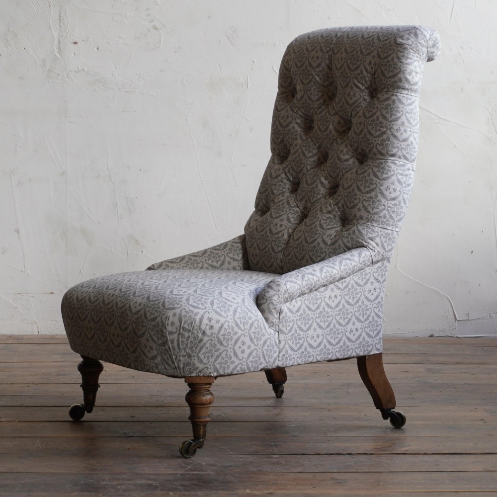A pair of low Victorian button-back armchairs with turned wooden legs and brass castors, one in calico and one in patterned grey fabric. View IX