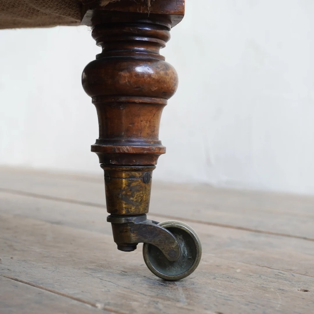 A pair of low Victorian button-back armchairs with turned wooden legs and brass castors, one in calico and one in patterned grey fabric. View XII