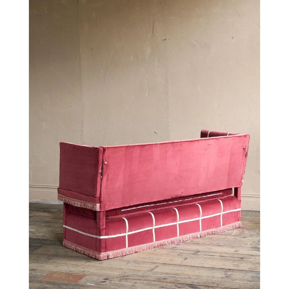 A claret red velvet Knole sofa featuring grid pattern braid trim, fringe edging, and adjustable drop-down armrests with metal ratchets. View VII
