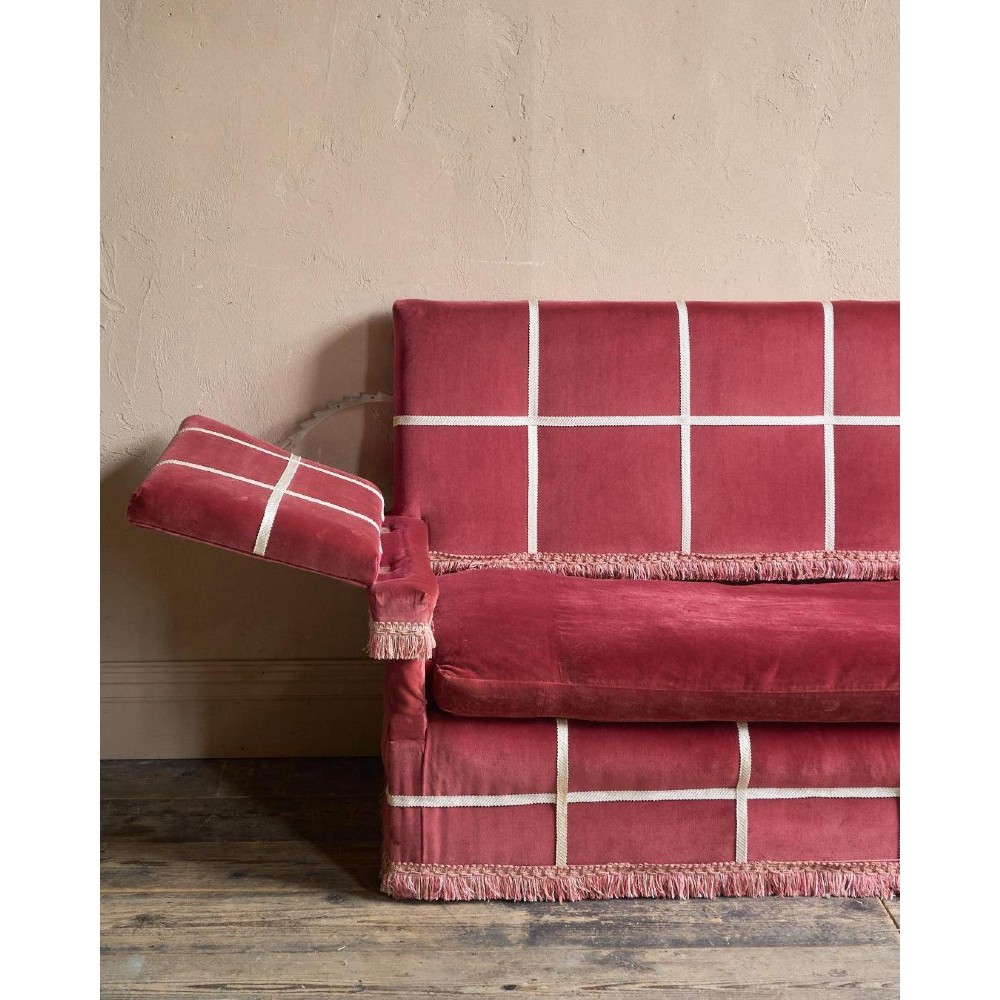 A claret red velvet Knole sofa featuring grid pattern braid trim, fringe edging, and adjustable drop-down armrests with metal ratchets. View XII