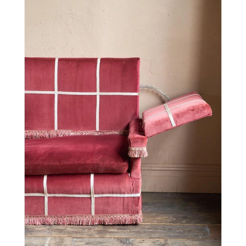 A claret red velvet Knole sofa featuring grid pattern braid trim, fringe edging, and adjustable drop-down armrests with metal ratchets. View XIII