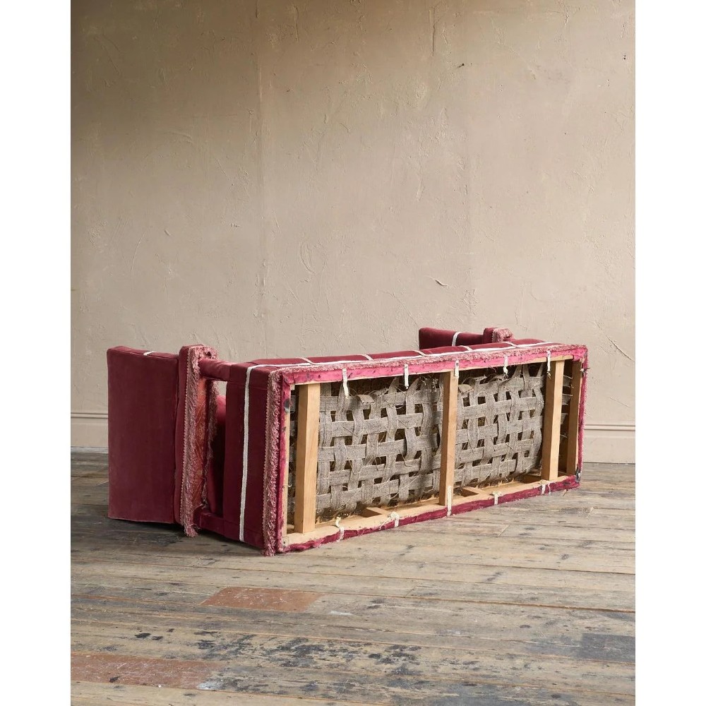 A claret red velvet Knole sofa featuring grid pattern braid trim, fringe edging, and adjustable drop-down armrests with metal ratchets. View XV