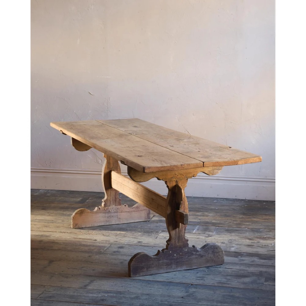 An 18th-century Swedish pine dining table featuring a rectangular plank top resting on a sculpted trestle base with a central stretcher.
