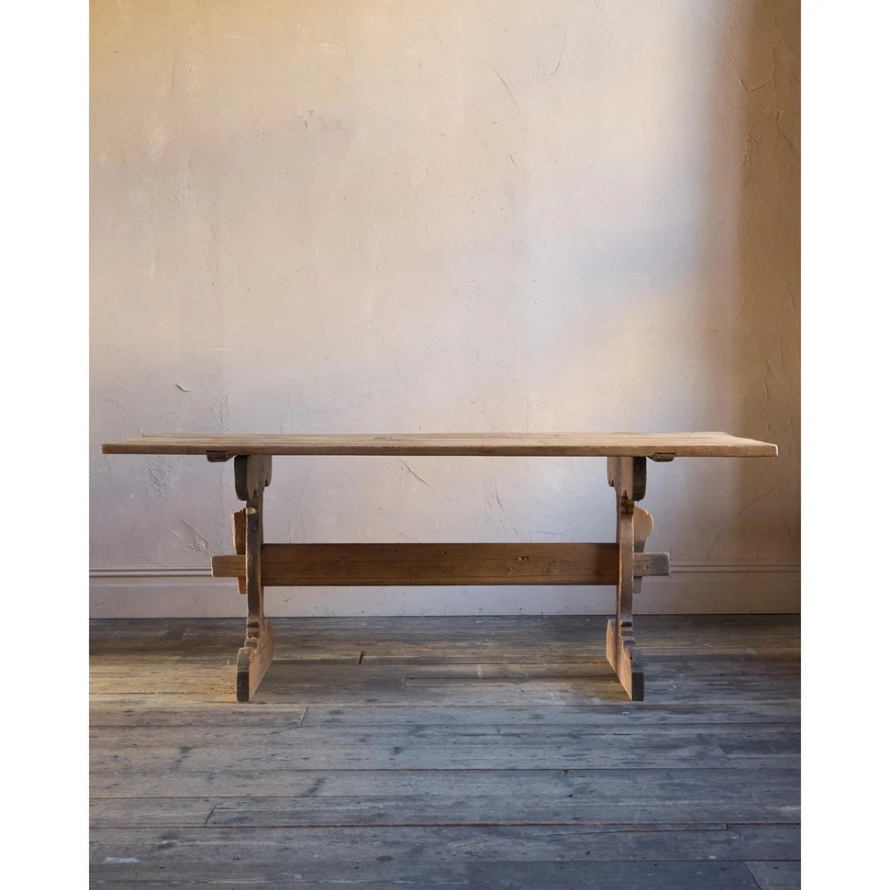 An 18th-century Swedish pine dining table featuring a rectangular plank top resting on a sculpted trestle base with a central stretcher. View V