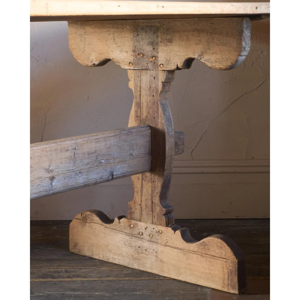 An 18th-century Swedish pine dining table featuring a rectangular plank top resting on a sculpted trestle base with a central stretcher. View VII