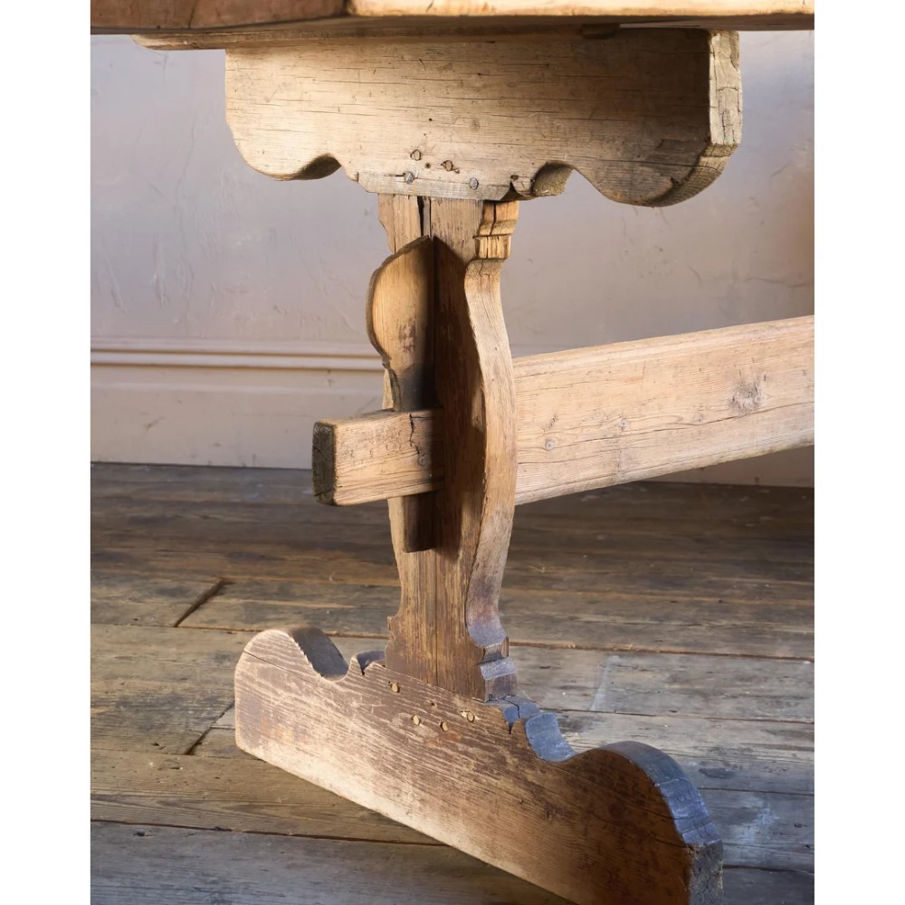An 18th-century Swedish pine dining table featuring a rectangular plank top resting on a sculpted trestle base with a central stretcher. View XI
