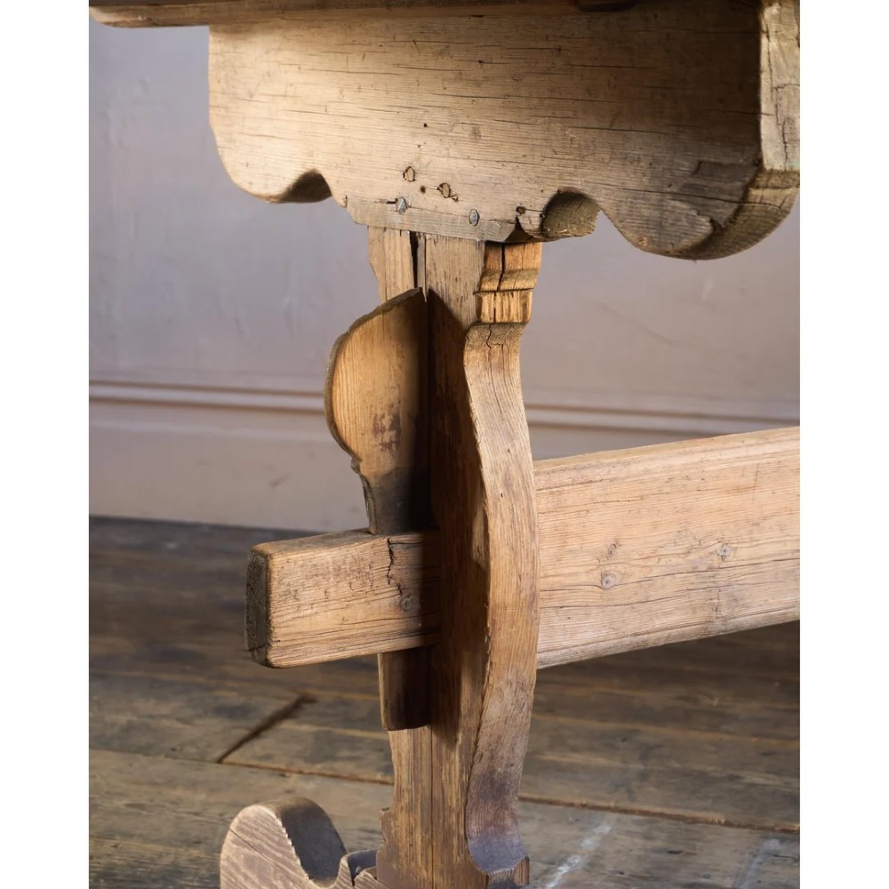 An 18th-century Swedish pine dining table featuring a rectangular plank top resting on a sculpted trestle base with a central stretcher. View XIII