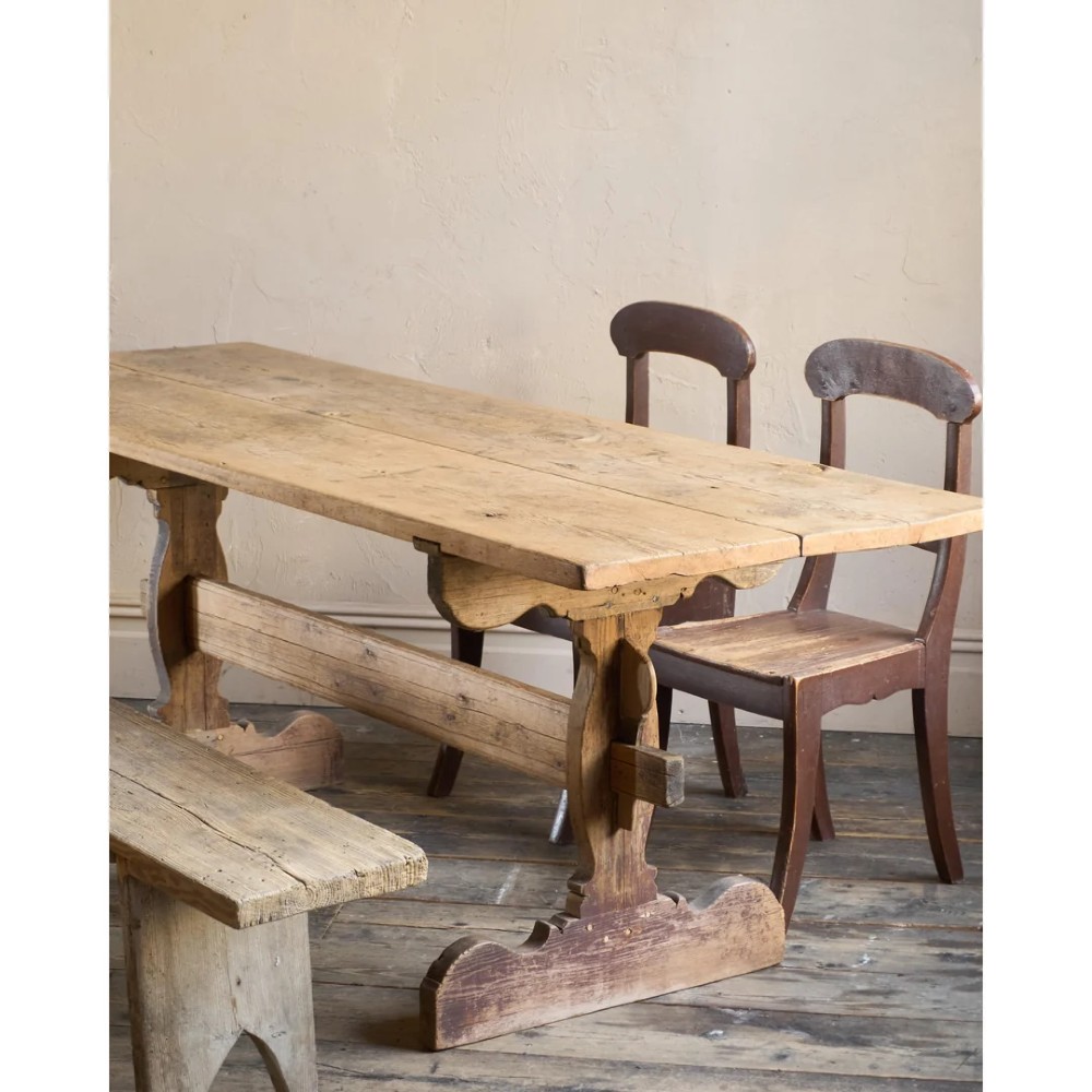 An 18th-century Swedish pine dining table featuring a rectangular plank top resting on a sculpted trestle base with a central stretcher. View XV