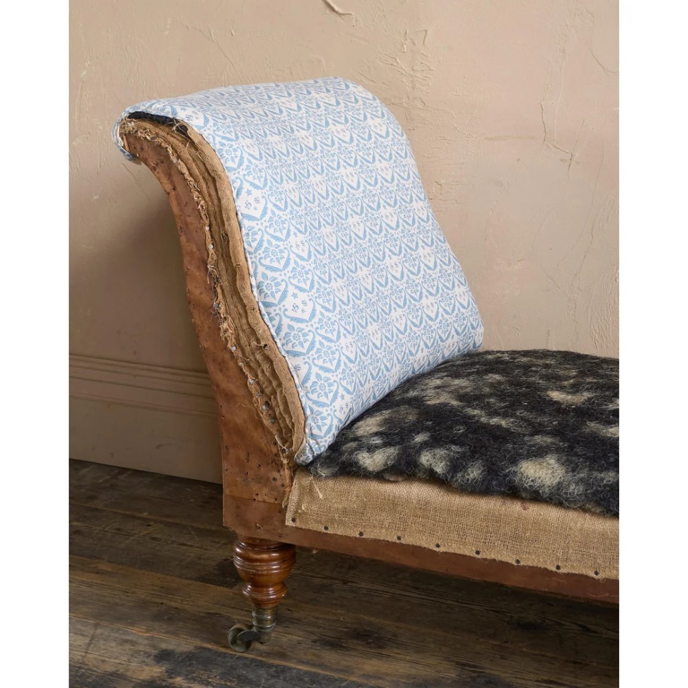 A 19th-century upholstered chaise longue with turned wooden legs on brass castors, patterned fabric backrest, hessian base, and cream bolster cushion. View XIII