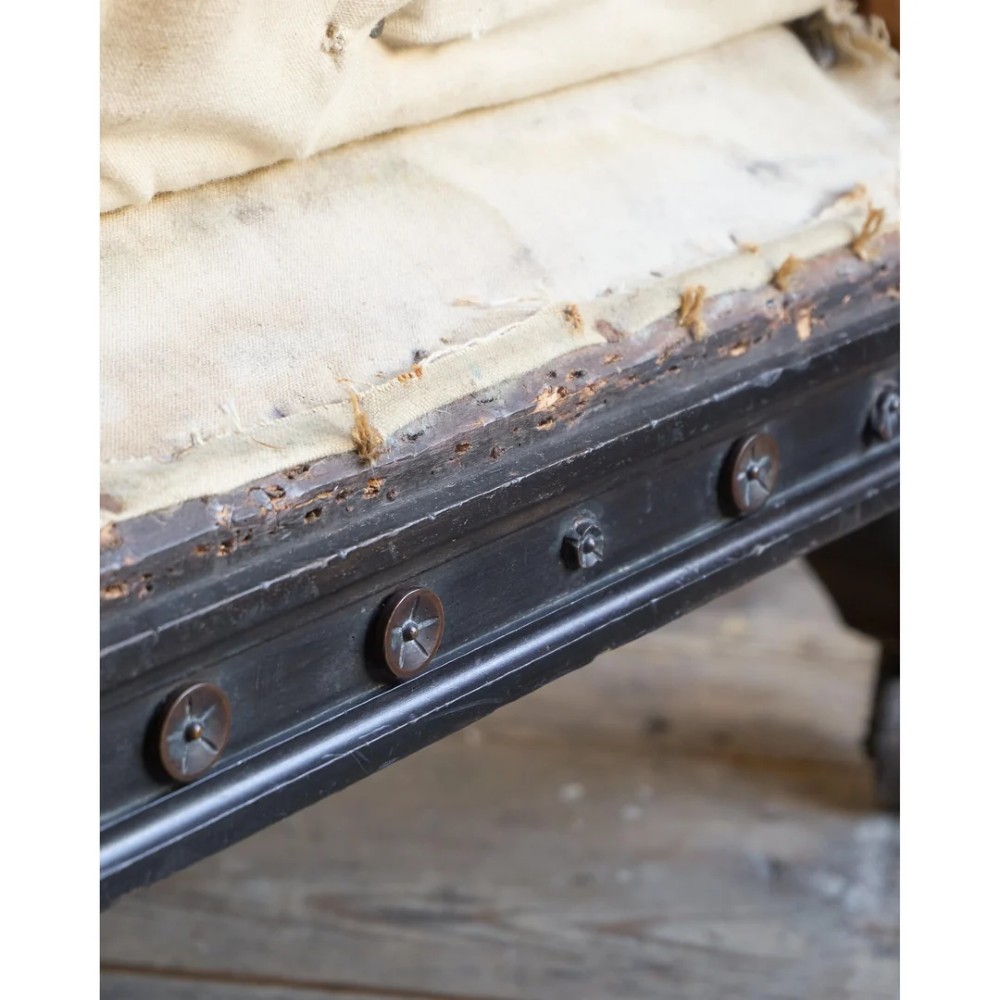 An antique Aesthetic Movement Chesterfield sofa featuring off-white upholstery, rolled arms, a dark carved timber frame, and turned legs with castors. View XII