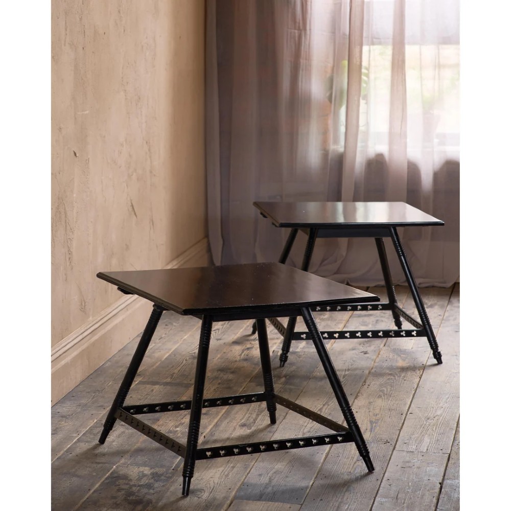 A matched pair of square ebonised wooden side tables with splayed turned legs and decorative pierced lower stretchers.