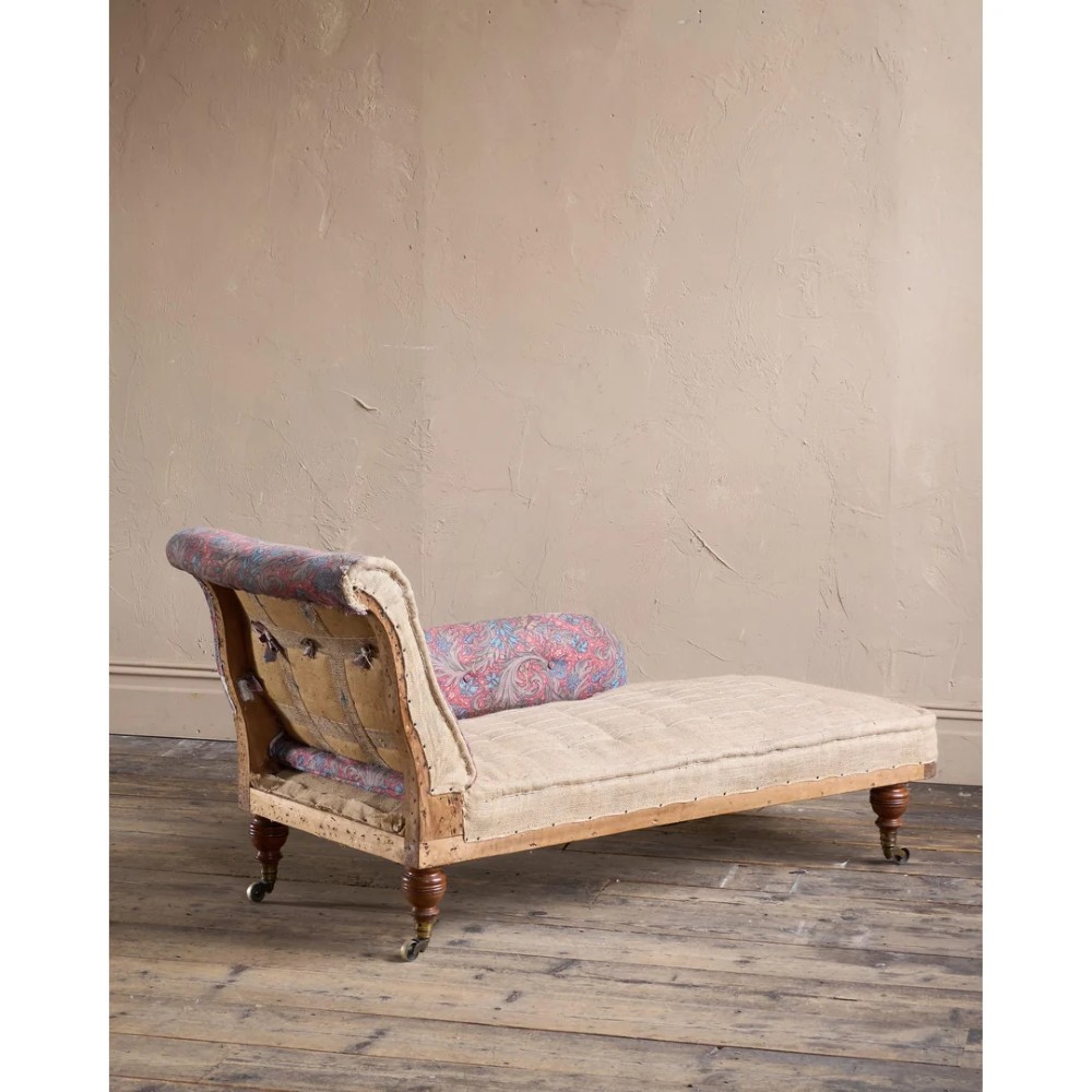 An antique Victorian chaise longue by Howard and Sons featuring patterned fabric upholstery, a single armrest, turned legs, and brass castors. View III