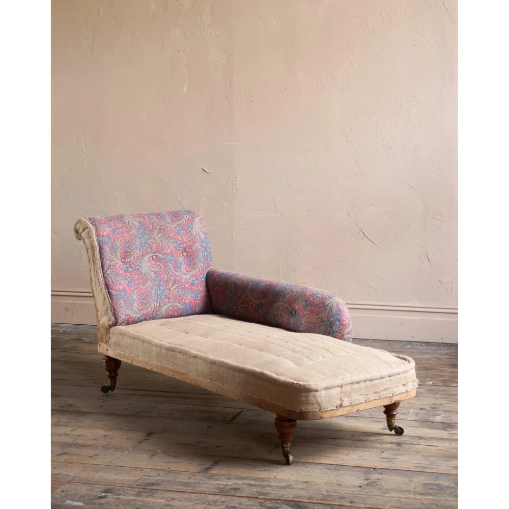 An antique Victorian chaise longue by Howard and Sons featuring patterned fabric upholstery, a single armrest, turned legs, and brass castors. View IV