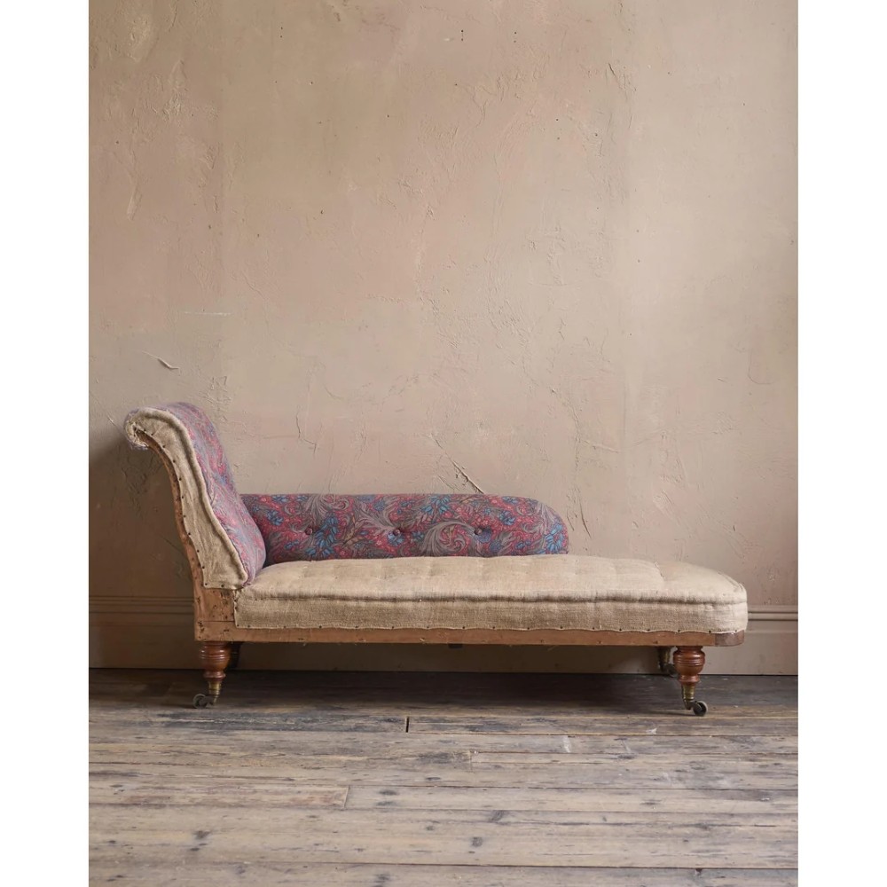 An antique Victorian chaise longue by Howard and Sons featuring patterned fabric upholstery, a single armrest, turned legs, and brass castors. View VIII