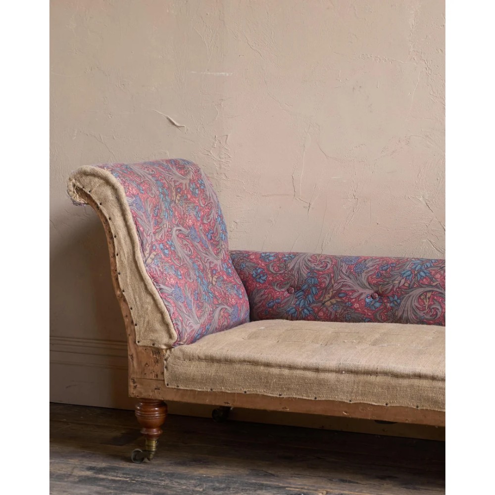 An antique Victorian chaise longue by Howard and Sons featuring patterned fabric upholstery, a single armrest, turned legs, and brass castors. View IX