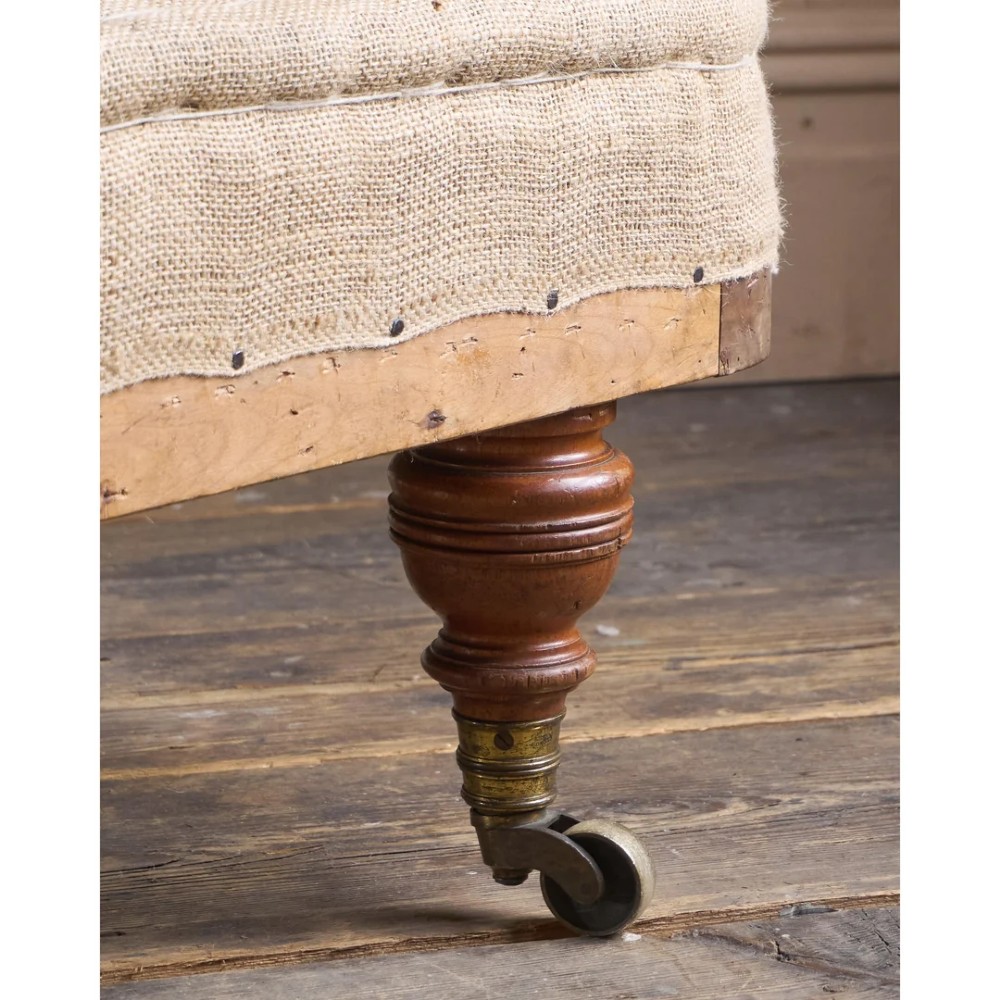 An antique Victorian chaise longue by Howard and Sons featuring patterned fabric upholstery, a single armrest, turned legs, and brass castors. View XV