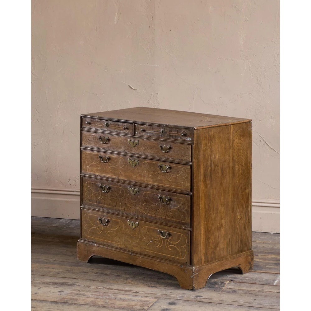 A late 17th-century William and Mary oak chest of drawers featuring geometric scrollwork inlay and brass drop handles. View II