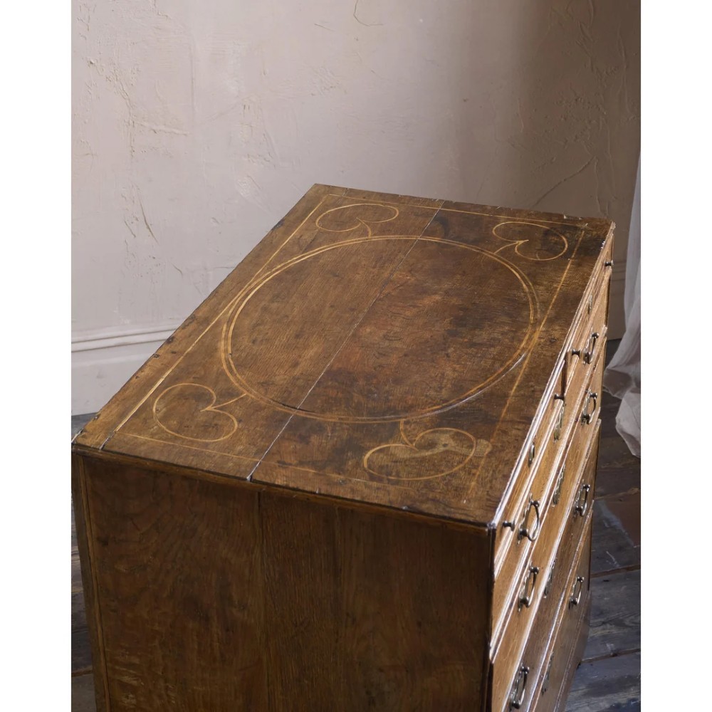 A late 17th-century William and Mary oak chest of drawers featuring geometric scrollwork inlay and brass drop handles. View IV