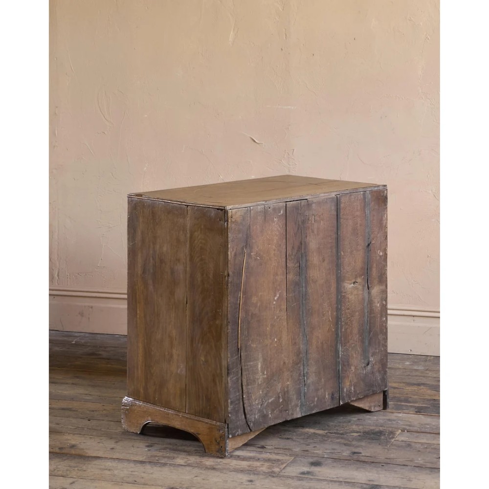 A late 17th-century William and Mary oak chest of drawers featuring geometric scrollwork inlay and brass drop handles. View V