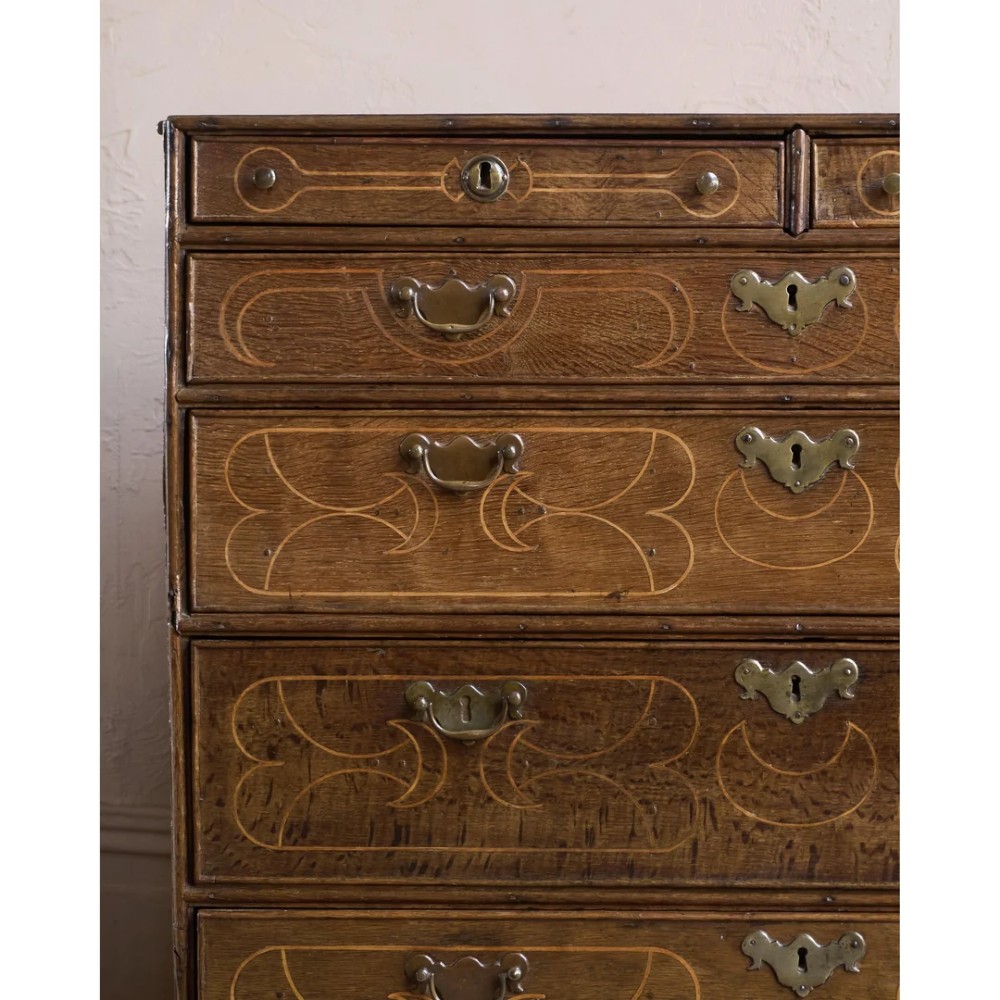 A late 17th-century William and Mary oak chest of drawers featuring geometric scrollwork inlay and brass drop handles. View VII