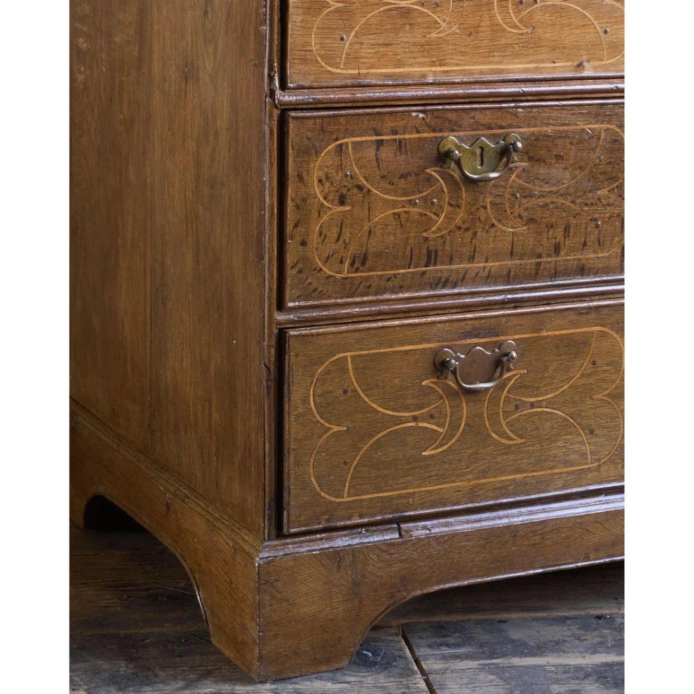 A late 17th-century William and Mary oak chest of drawers featuring geometric scrollwork inlay and brass drop handles. View IX