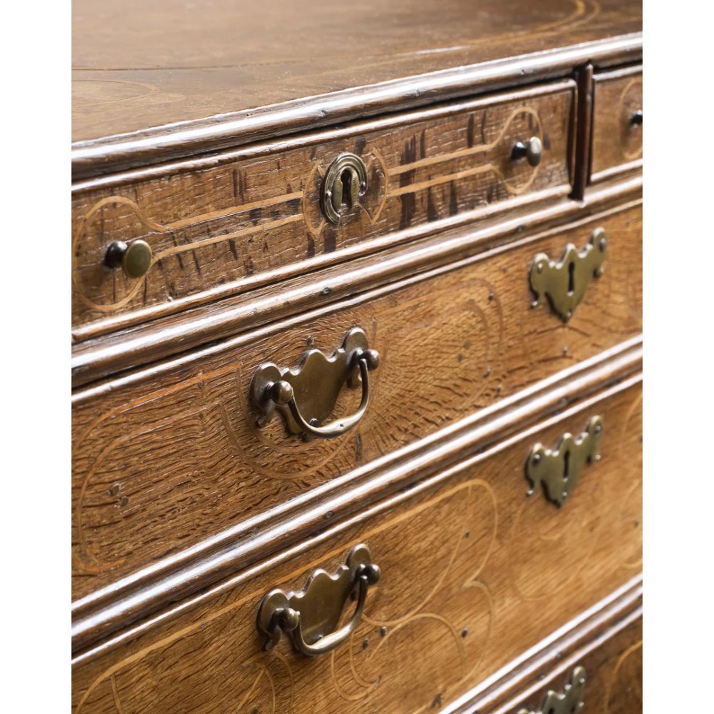 A late 17th-century William and Mary oak chest of drawers featuring geometric scrollwork inlay and brass drop handles. View XIV