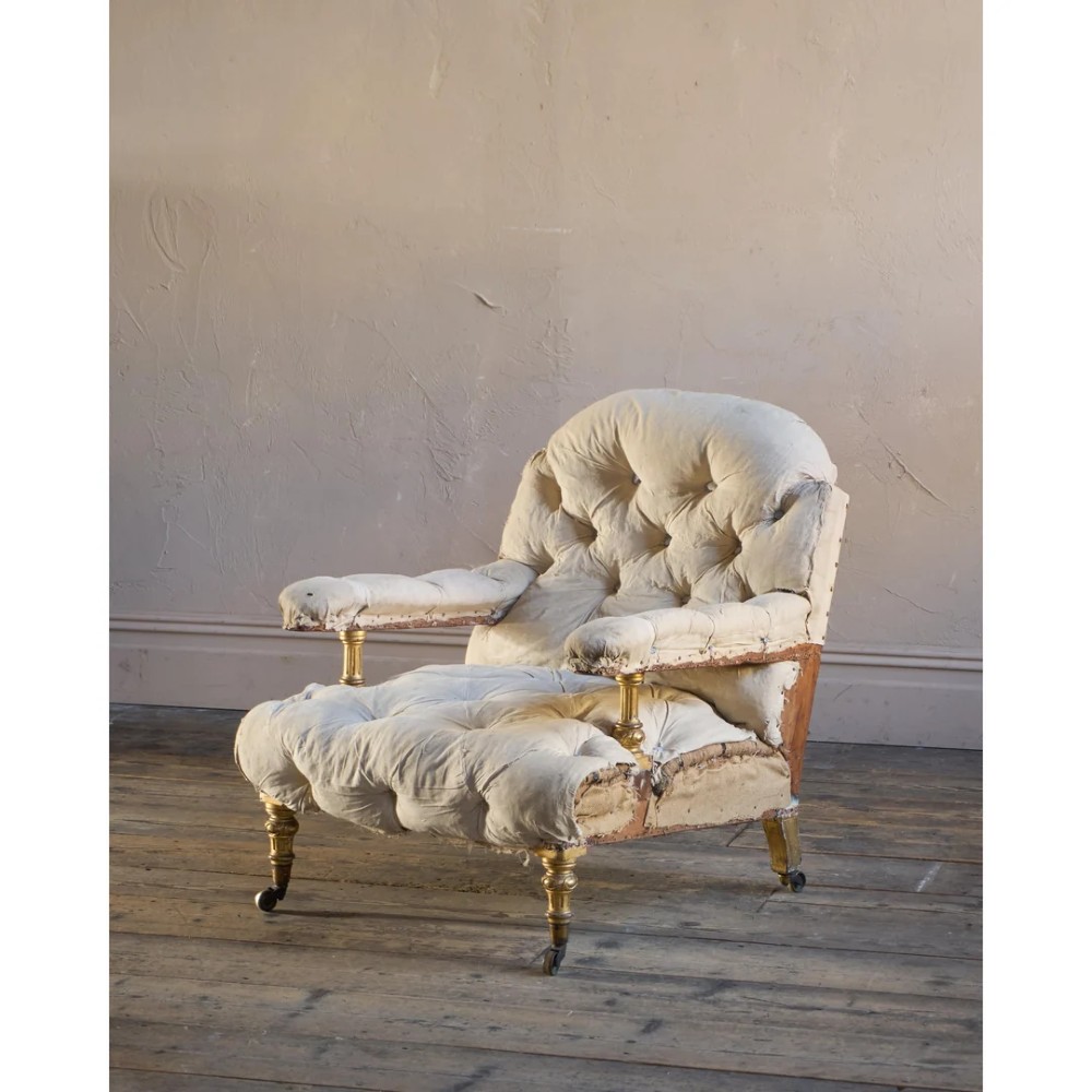 A Victorian open armchair upholstered in off-white calico fabric with deep buttoning, padded armrests, turned legs, and brass castors. View II