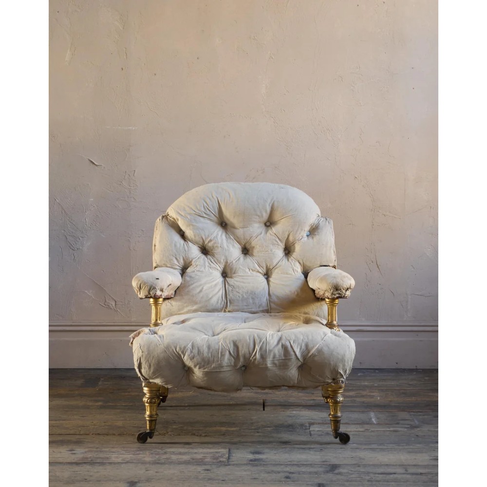 A Victorian open armchair upholstered in off-white calico fabric with deep buttoning, padded armrests, turned legs, and brass castors. View III
