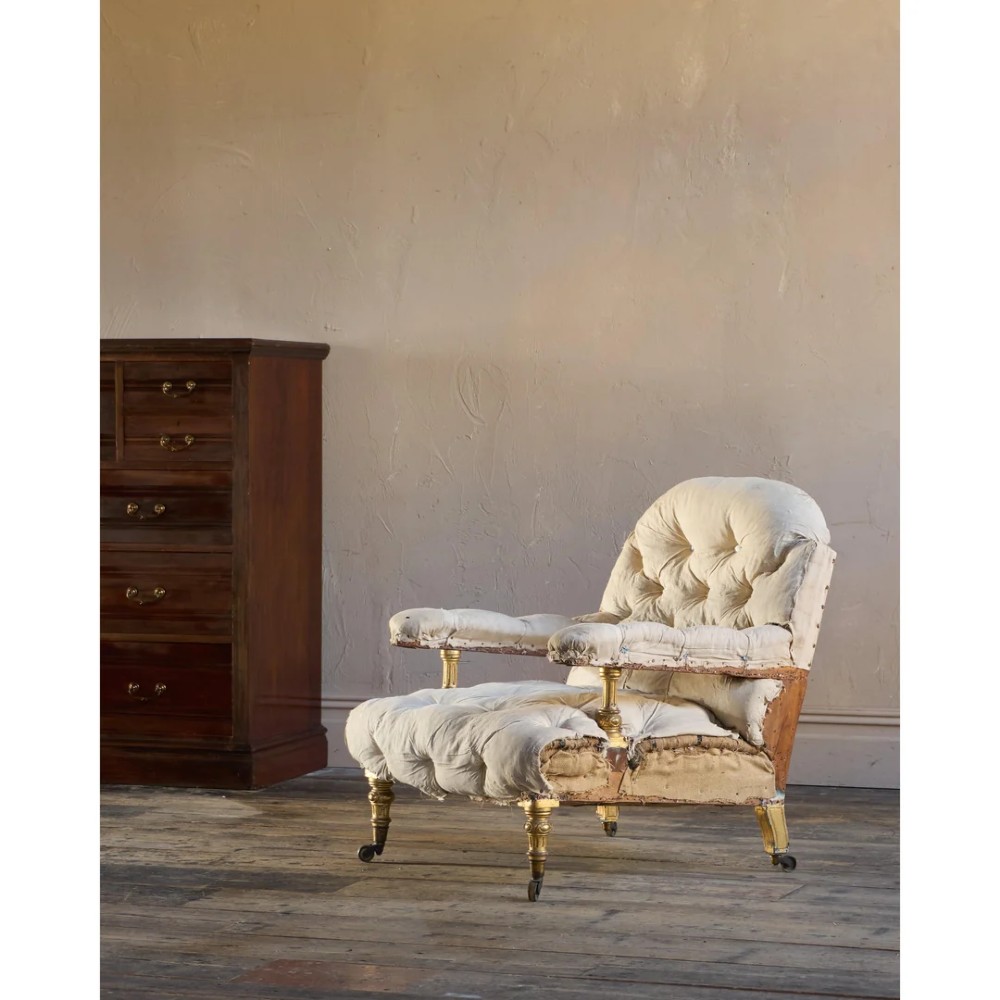 A Victorian open armchair upholstered in off-white calico fabric with deep buttoning, padded armrests, turned legs, and brass castors. View IV