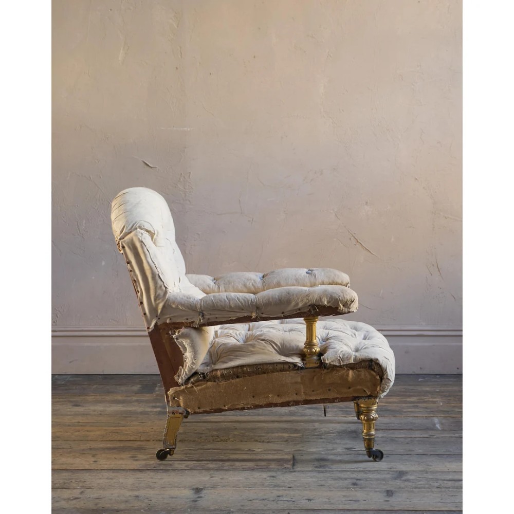 A Victorian open armchair upholstered in off-white calico fabric with deep buttoning, padded armrests, turned legs, and brass castors. View VI