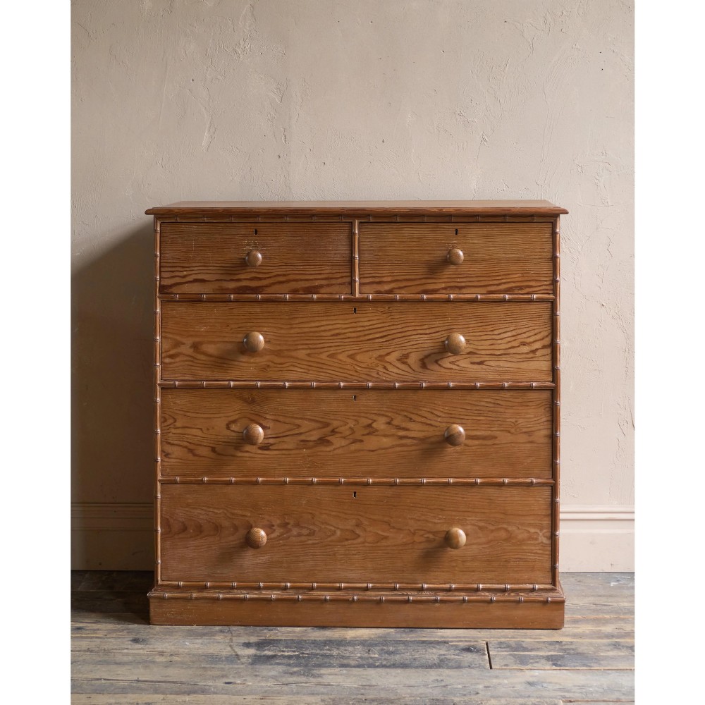 A Victorian pitch pine chest of drawers featuring two short over three long drawers framed with carved faux bamboo mouldings and turned wooden knobs. View II