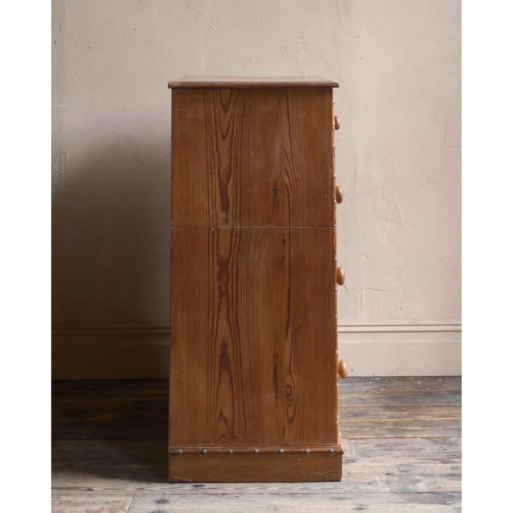 A Victorian pitch pine chest of drawers featuring two short over three long drawers framed with carved faux bamboo mouldings and turned wooden knobs. View V