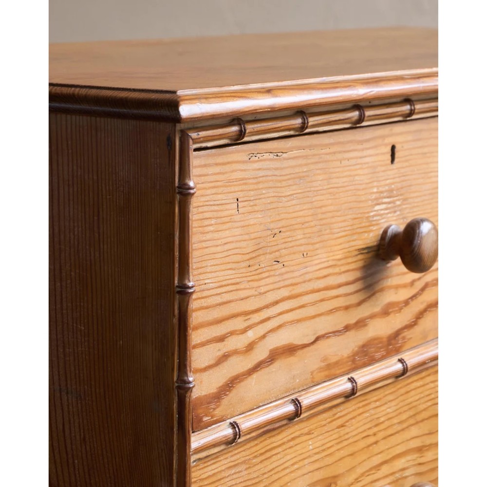 A Victorian pitch pine chest of drawers featuring two short over three long drawers framed with carved faux bamboo mouldings and turned wooden knobs. View VII