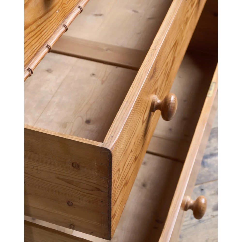 A Victorian pitch pine chest of drawers featuring two short over three long drawers framed with carved faux bamboo mouldings and turned wooden knobs. View VIII
