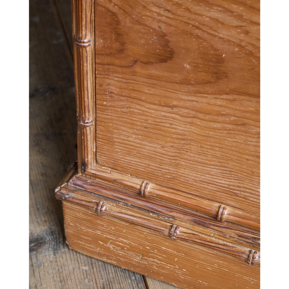 A Victorian pitch pine chest of drawers featuring two short over three long drawers framed with carved faux bamboo mouldings and turned wooden knobs. View X