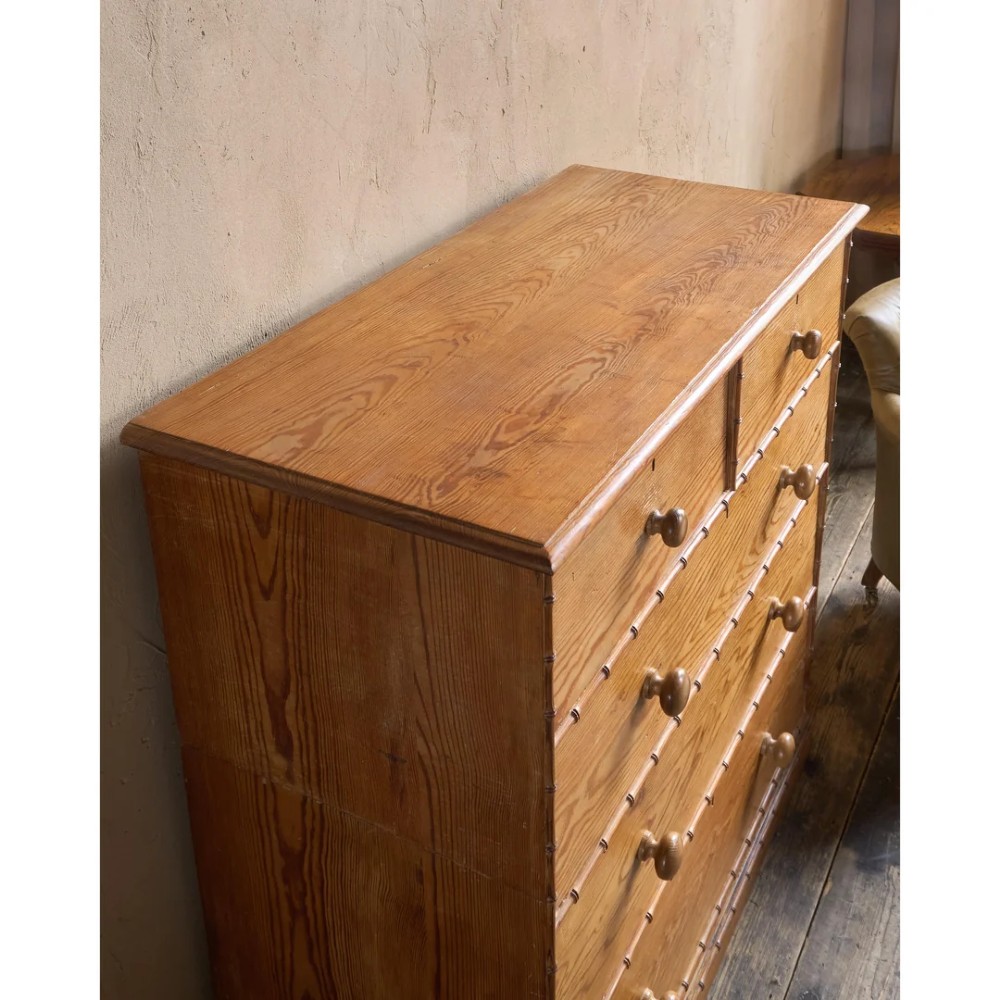 A Victorian pitch pine chest of drawers featuring two short over three long drawers framed with carved faux bamboo mouldings and turned wooden knobs. View XII