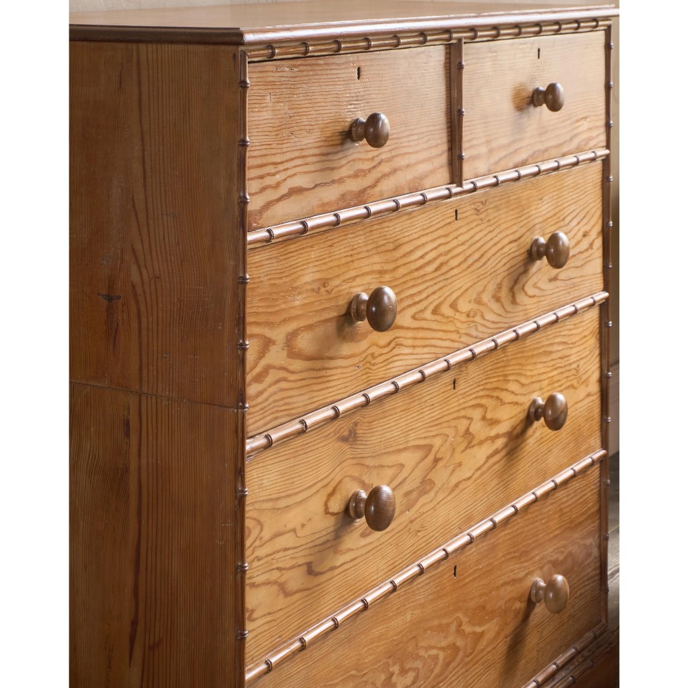 A Victorian pitch pine chest of drawers featuring two short over three long drawers framed with carved faux bamboo mouldings and turned wooden knobs. View XIV