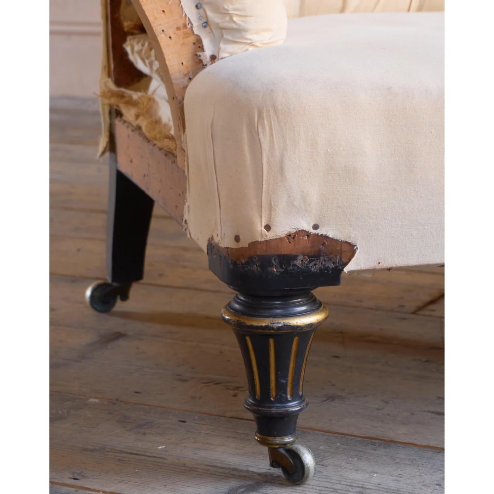 A Victorian two-seater sofa featuring deep button-tufted off-white calico upholstery, scroll arms, and turned front legs with brass castors. View VIII