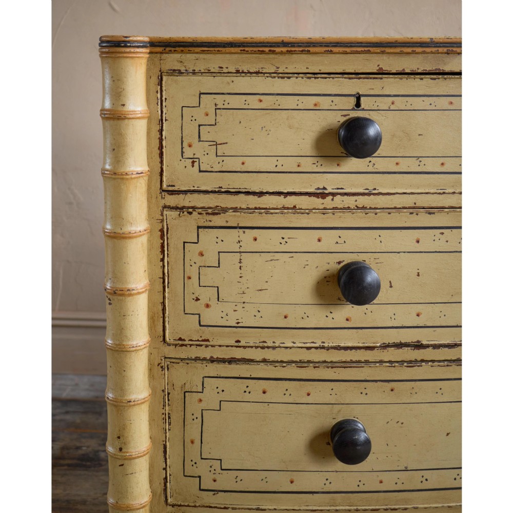 A Regency pale yellow painted chest of drawers featuring simulated bamboo turned corner columns and dark turned knobs. View X
