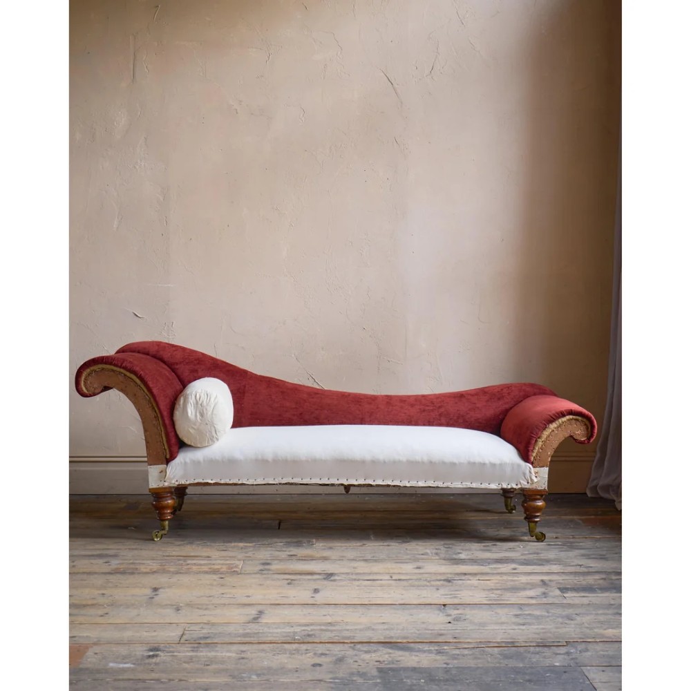 A Victorian asymmetrical chaise longue featuring red velvet and white calico fabric upholstery set on turned mahogany legs with brass castors. View II