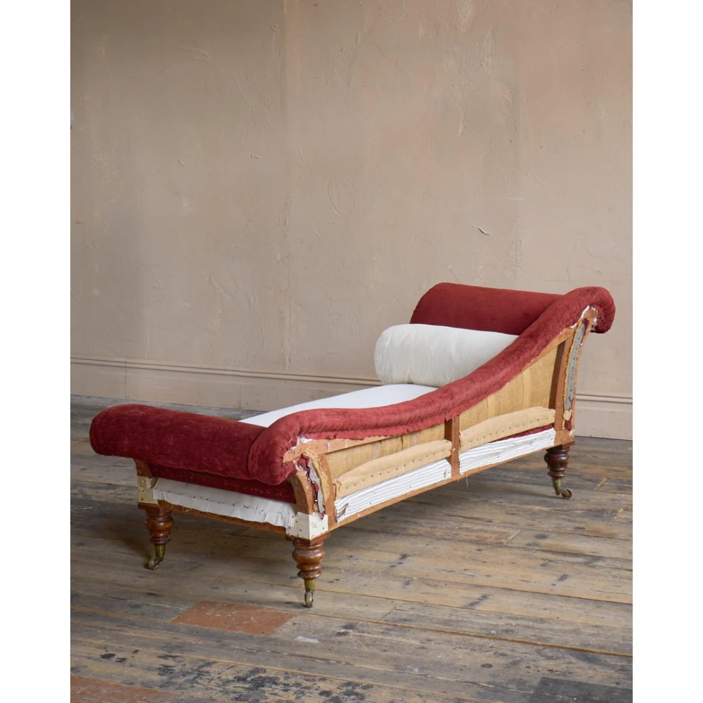 A Victorian asymmetrical chaise longue featuring red velvet and white calico fabric upholstery set on turned mahogany legs with brass castors. View III